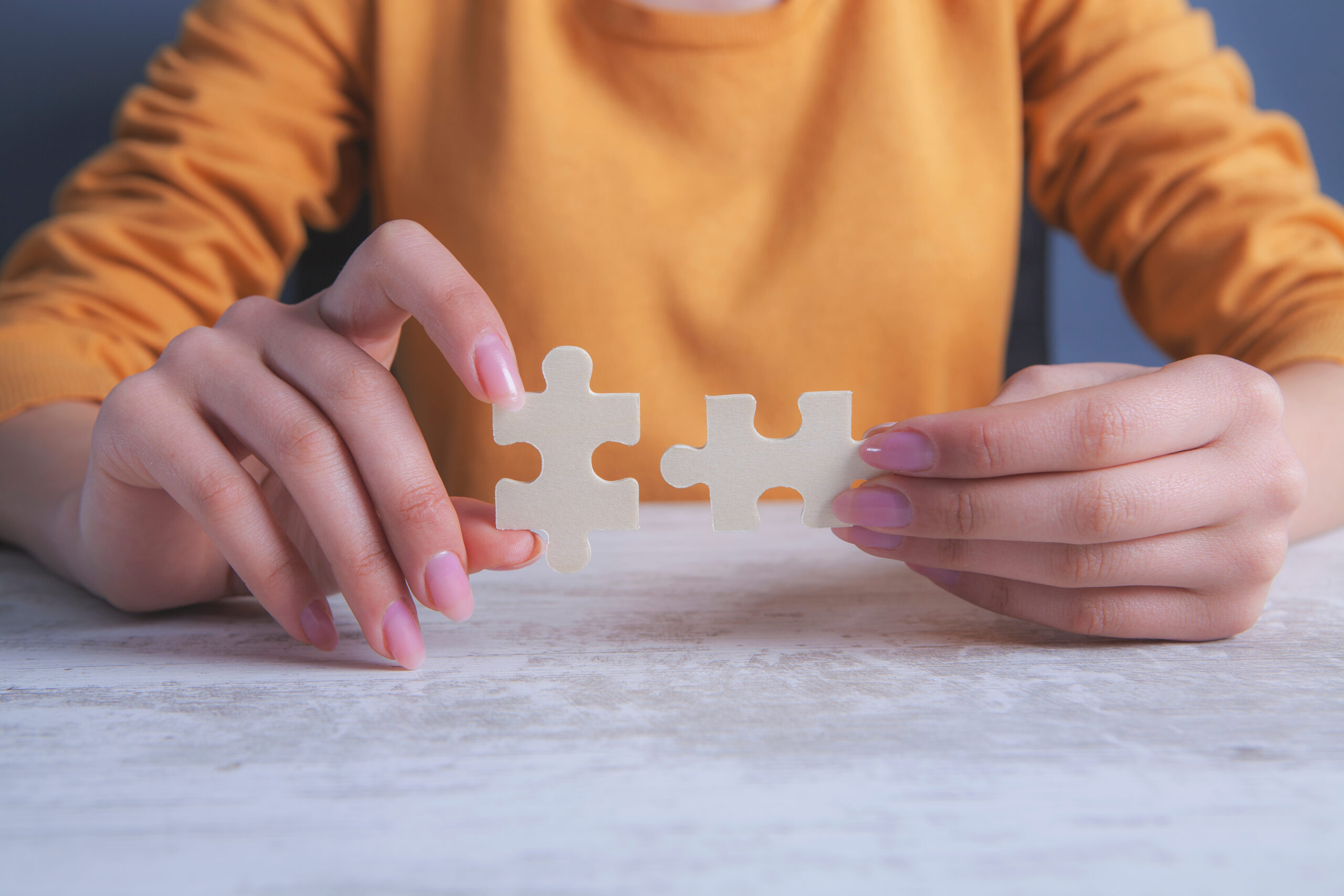 Eine Frau hält zwei Puzzleteile aneinander.